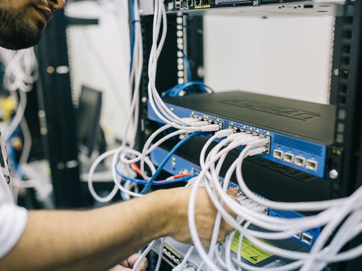 Technician connecting network cables in a data centre server rack